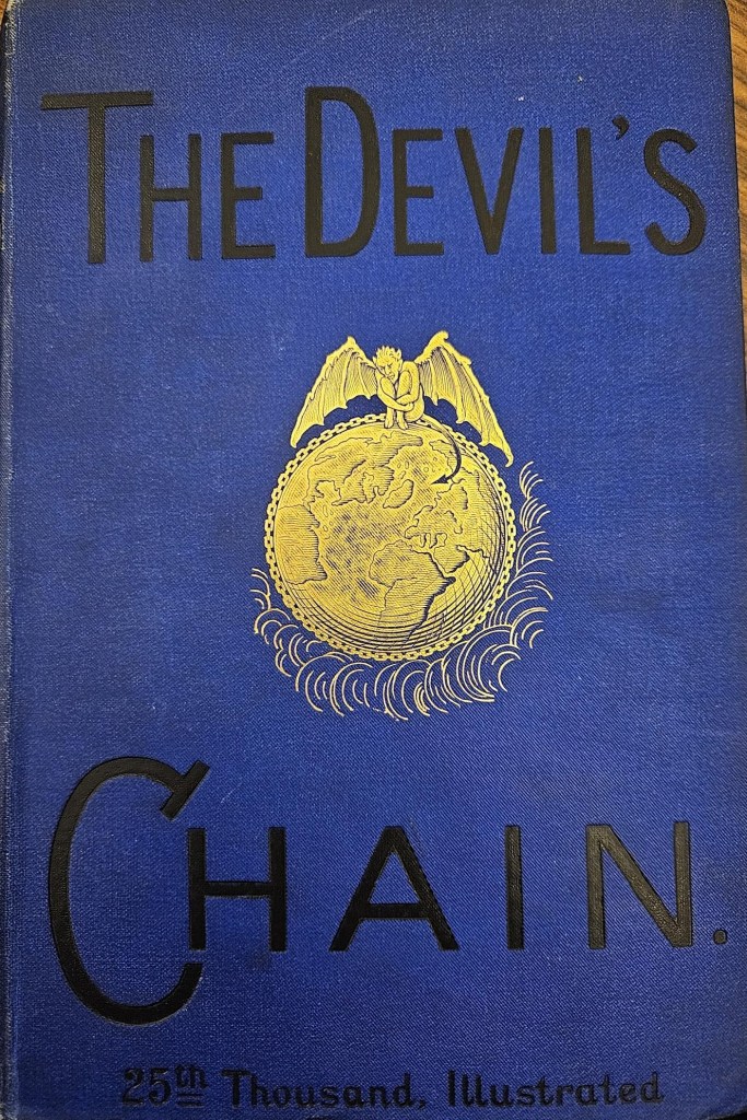 A picture of the cover of Devil's Chain. Cover is blue with the image of a devil with wings and a tail standing on top of the world in gold foil. 